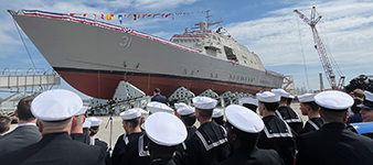 Sailors in uniform and white caps looking at the docked ship
